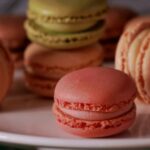 a white plate topped with lots of pink and green macaroons