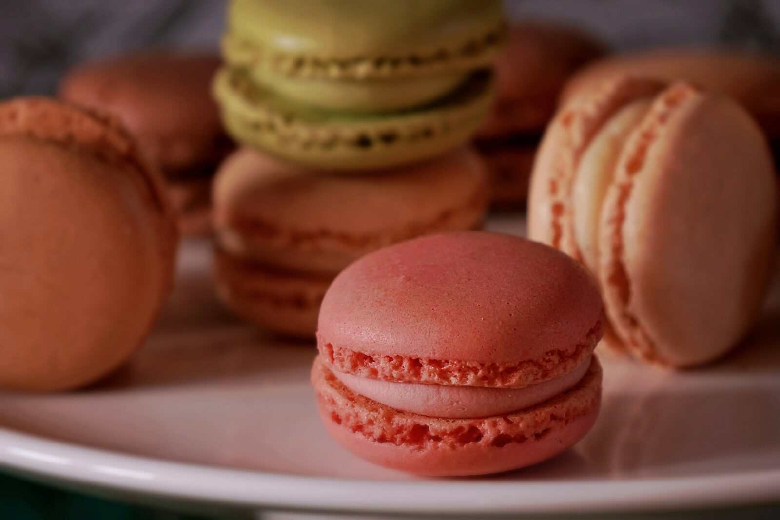a white plate topped with lots of pink and green macaroons