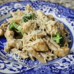 a blue and white plate topped with pasta and broccoli