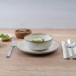Bowl of soup with ingredients and cutlery on table