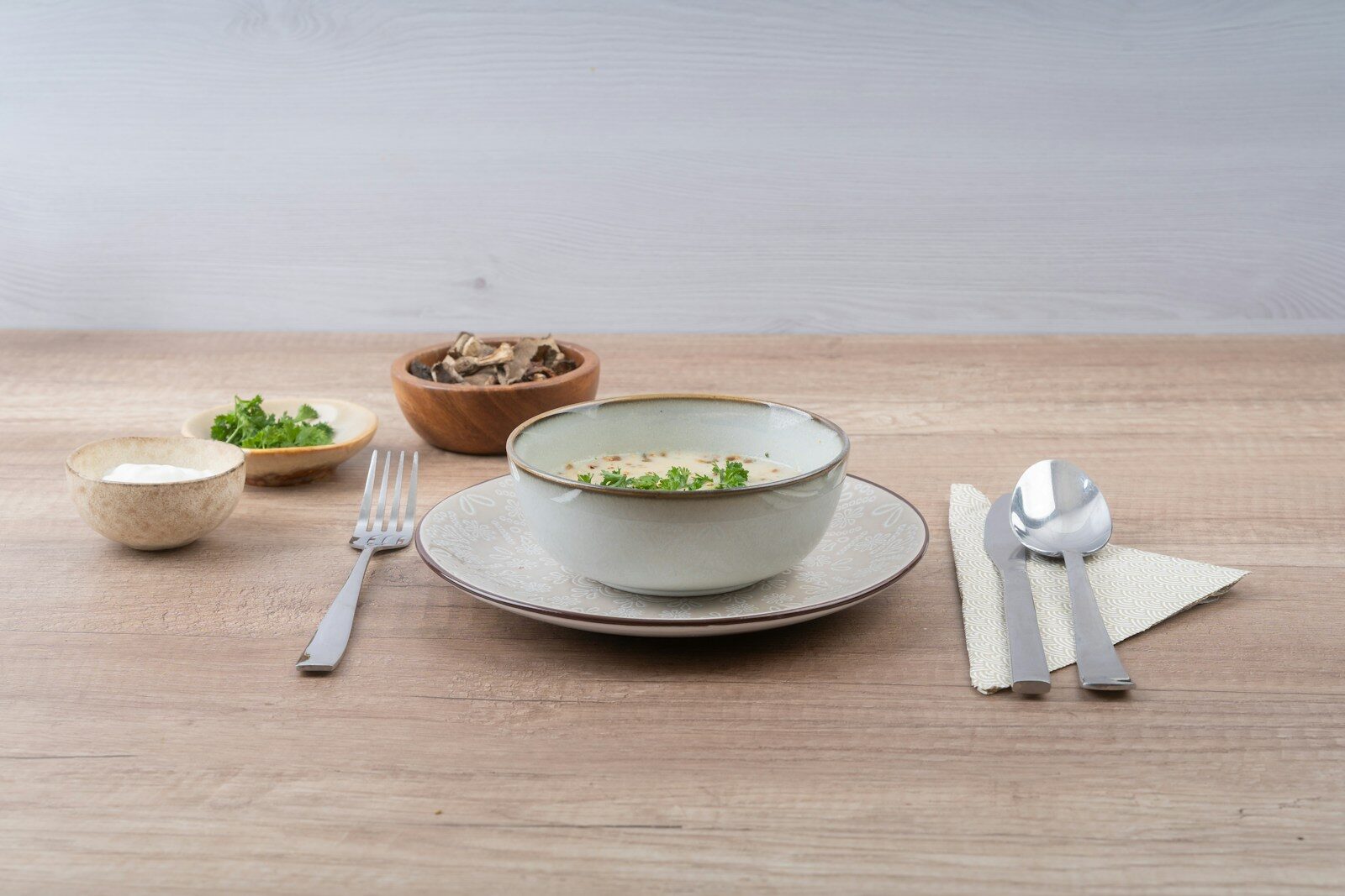 Bowl of soup with ingredients and cutlery on table
