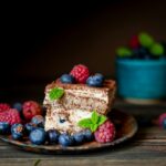 A slice of chocolate cake topped with berries and mint