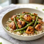 Healthy chicken and green bean stir-fry served over rice with glossy sauce and scallions