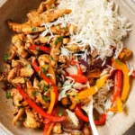 One pan chicken and peppers served on a plate with browned chicken, bell peppers, and red onion in a light sauce.