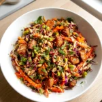 Asian chicken crunch salad in a bowl with cabbage, chicken, edamame, and chopped peanuts