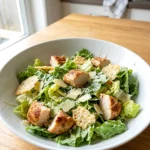 Keto chicken Caesar salad in a bowl with sliced chicken, romaine, Parmesan, and crisps