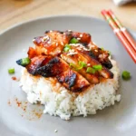 Spicy Korean chicken glazed and served with rice, green onions, and sesame seeds
