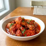 Nigerian chicken stew served in a bowl with thick red sauce coating the chicken