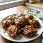 Plate of Korean soy garlic chicken thighs with glossy sauce, sesame seeds, and sliced green onions