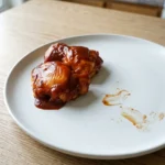 Low carb BBQ chicken thighs glazed with barbecue sauce on a simple dinner plate
