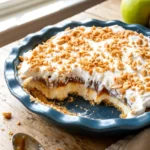 Caramel apple cheesecake dip in a pie dish with a section scooped out
