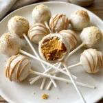 Pumpkin pie cake pops on sticks with white candy coating and pumpkin pie spice on top