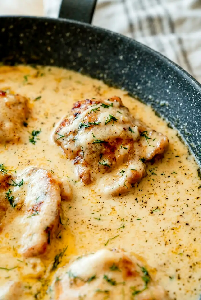 Close-up of creamy oven baked chicken thighs with browned edges and smooth Parmesan sauce