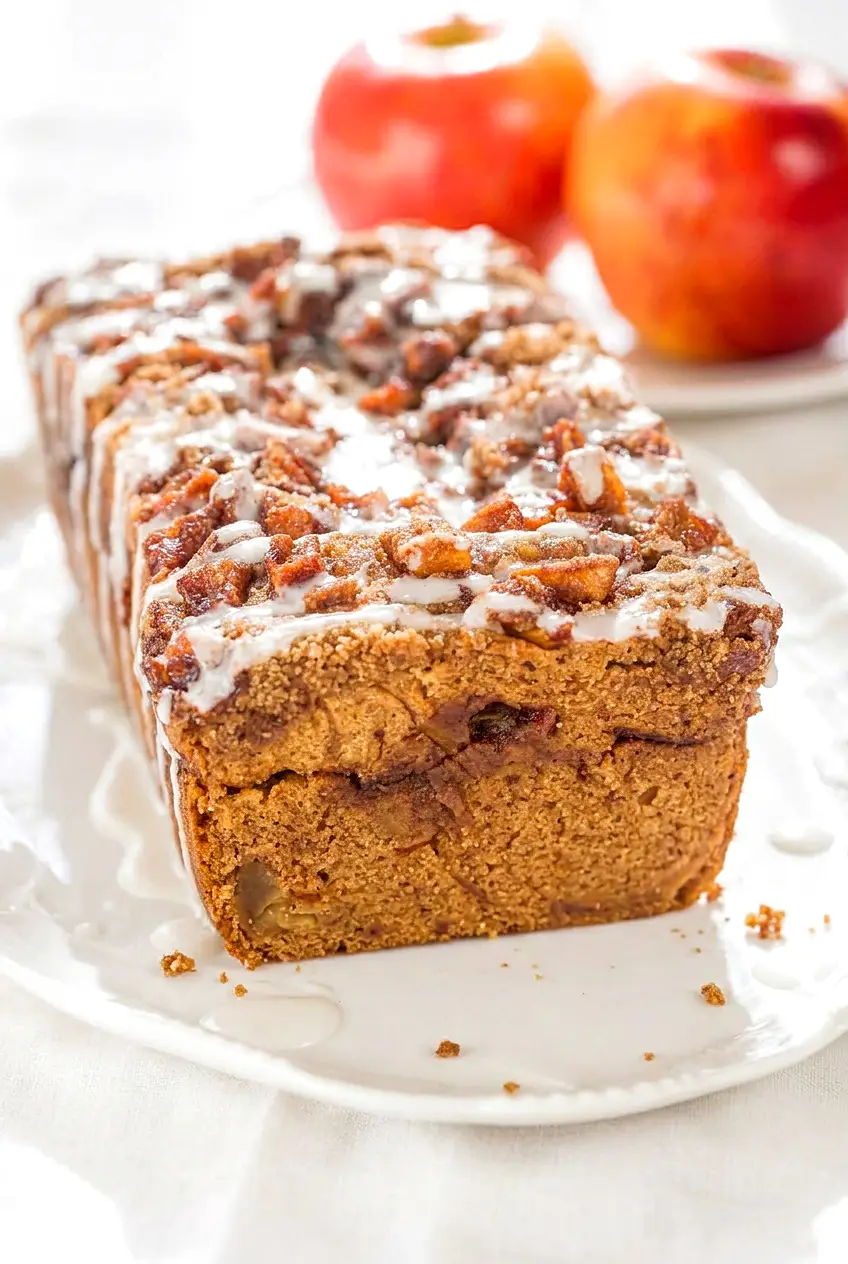 Close view of apple fritter bread showing the glazed top and cinnamon swirl in the loaf