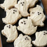 Ghost Rice Krispie treats with swirled white coating and chocolate-chip faces on a black platter