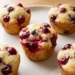 Plain cranberry orange muffins with whole cranberries baked into pale golden tops and unlined golden sides.