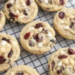 Thick white chocolate cranberry cookies with visible white chips and dried cranberries cooling on a wire rack.