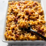 Baked mac and cheese with bacon and caramelized onions in a white rectangular casserole dish.