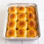 Golden garlic butter dinner rolls baked as a 3-by-4 pull-apart grid in a parchment-lined rectangular pan.