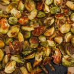 Parmesan roasted Brussels sprouts with browned cut sides and crisp garlic-cheese bits on a parchment-lined sheet pan.