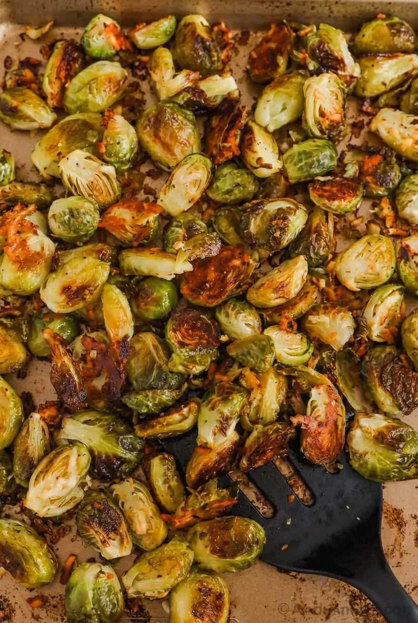 Parmesan roasted Brussels sprouts with browned cut sides and crisp garlic-cheese bits on a parchment-lined sheet pan.