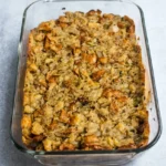 Grandma’s Thanksgiving dressing baked in a clear glass casserole with golden bread cubes, celery, and onion.