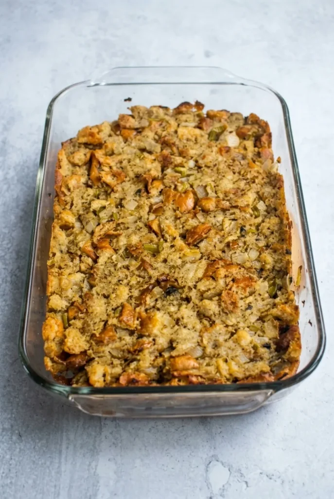 Grandma’s Thanksgiving dressing baked in a clear glass casserole with golden bread cubes, celery, and onion.
