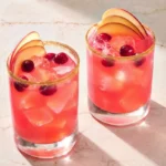 Two cranberry-apple Thanksgiving margaritas with cinnamon-sugar rims, apple fans, cranberries, and large ice cubes.
