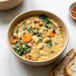 Tuscan white bean soup with cannellini beans, carrots, kale, parsley, and red pepper flakes in a rustic ceramic bowl.