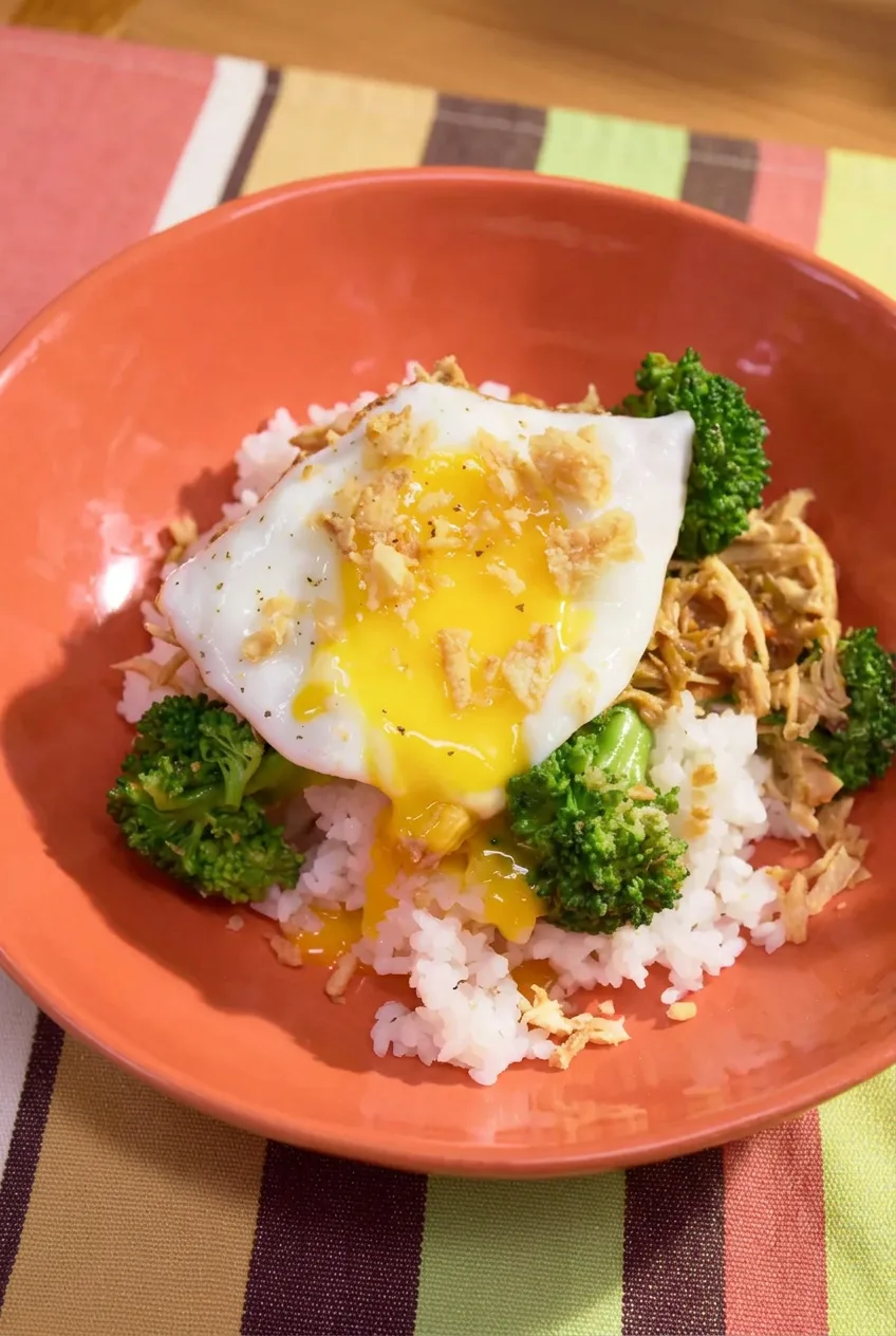 Teriyaki chicken and broccoli rice bowl topped with a fried egg and crispy onions