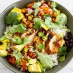 Chicken taco rice bowl with sliced browned chicken, white rice, pico, avocado, and green sauce