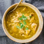 Full bowl of chicken chili verde with tender chicken pieces, thick green sauce, and cilantro