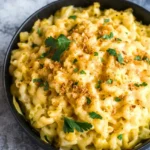 Chick-fil-A-style mac and cheese in a round black dish with browned cheddar, sparse crumbs, and parsley