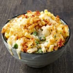 Heaped bowl of cauliflower mac and cheese with peas, creamy sauce and golden breadcrumb patches