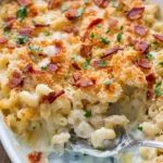 Spoon lifting creamy five cheese mac and cheese beneath golden panko, bacon, and parsley
