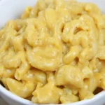 White bowl heaped with no-boil Crockpot mac and cheese in glossy golden sauce