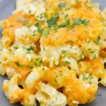 Paula Deen-style mac and cheese piled loosely on a gray plate with melted cheddar and parsley