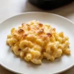A generous scoop of Patti LaBelle-style mac and cheese with creamy elbows and browned cheese on a light plate