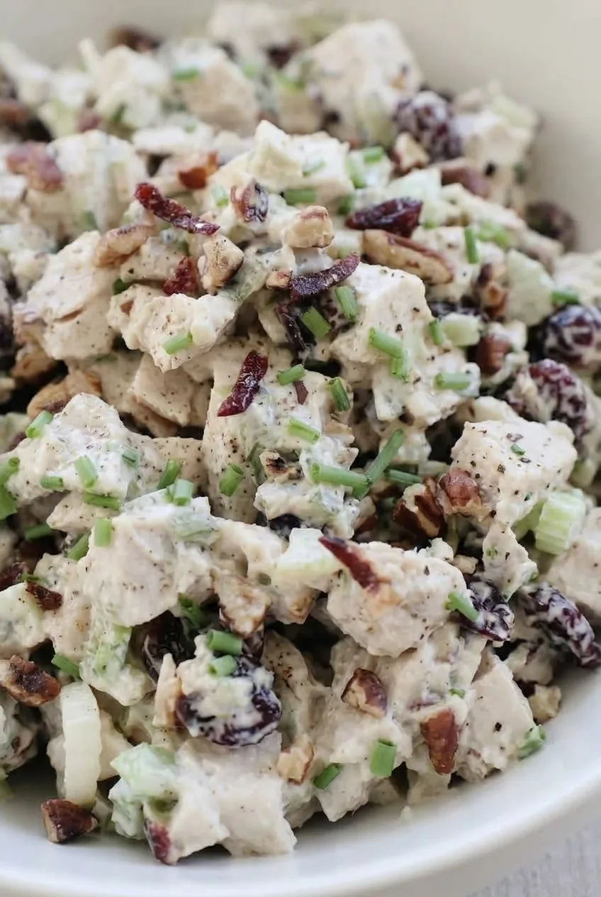 Close view of creamy Southern turkey salad showing turkey chunks, crisp celery, cranberries, pecans, and chives.