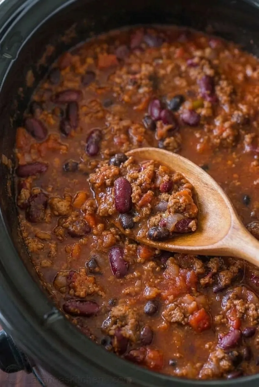 Close view of beef crumbles, kidney beans, and black beans in the chili's thick tomato sauce