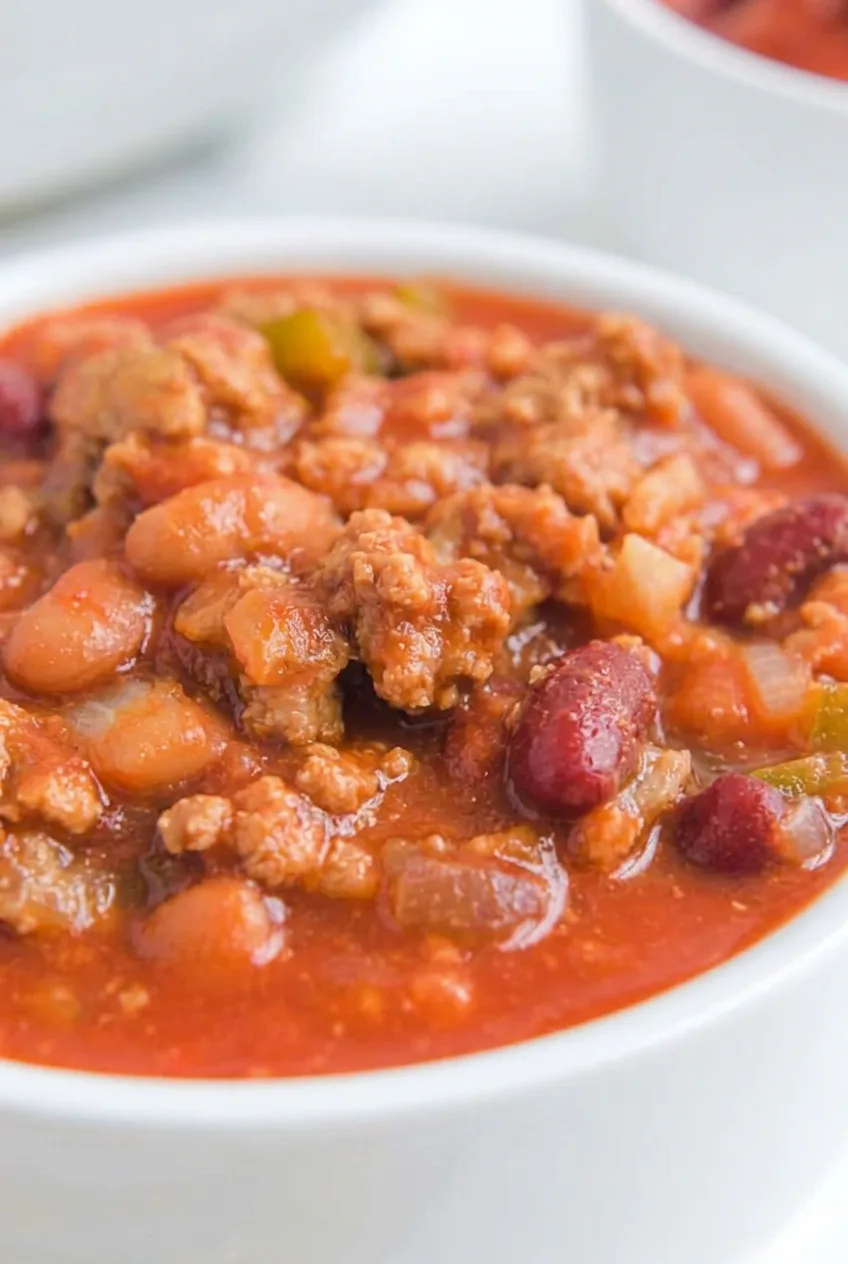 Close view of beef crumbles and whole beans in the chili’s glossy tomato sauce