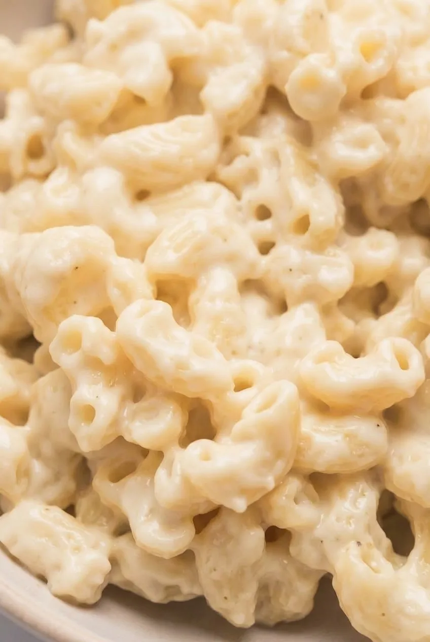 Close view of pale white cheddar sauce coating individual cavatappi curls