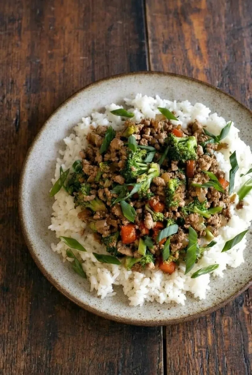 Overhead view of a ground turkey stir fry rice bowl with broccoli, red pepper, and sliced green onions.