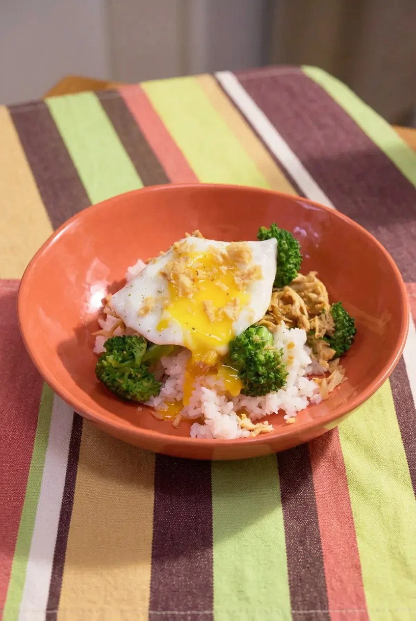 Complete teriyaki chicken and broccoli bowl with rice, fried egg, and crispy onions on a table