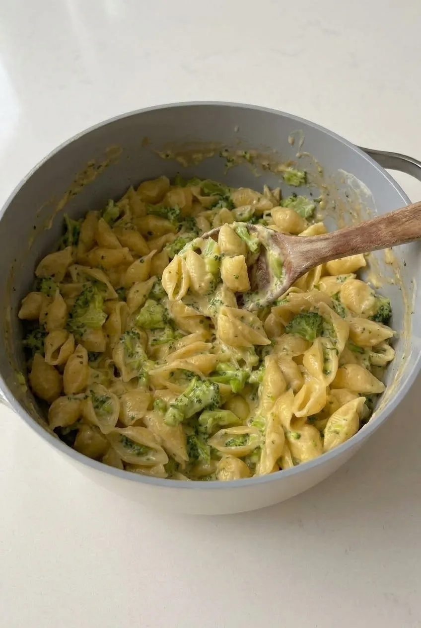 Full pot of creamy shell mac and cheese with broccoli on a neutral countertop