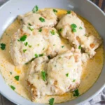 Cream cheese chicken in a shallow skillet with pale sauce, browned patches and chopped parsley