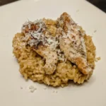 Chicken scampi tenderloins over glossy garlic Parmesan rice with Parmesan shavings on a square plate