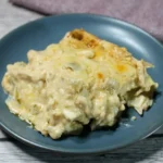 Two saucy low carb white chicken enchiladas with melted cheese on a blue-gray plate