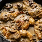 Chicken Marsala cutlets and sliced mushrooms in creamy tan sauce, served in a dark skillet