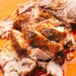 Thick pieces of Crock Pot pork loin with browned edges and glossy juices on a wooden board